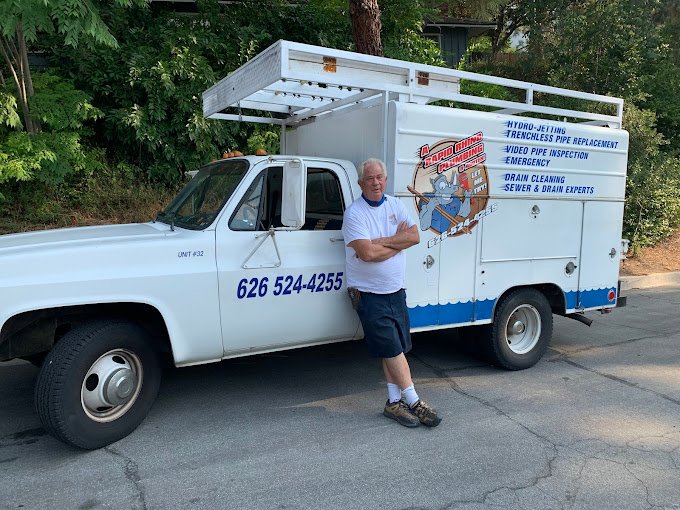 "Plumber standing proudly in front of a Rapid Rhino Plumbing service truck, ready to handle hydro-jetting, trenchless pipe replacement, drain cleaning, and emergency sewer repairs in Southern California. Call 626-524-4255."